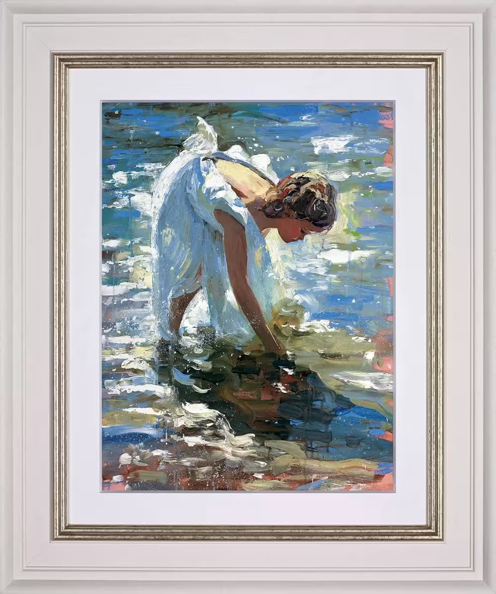 A Sherree Valentine Daines framed limited edition of a girl in a white dress picking something up from the water, the title is Adventures by the Sea