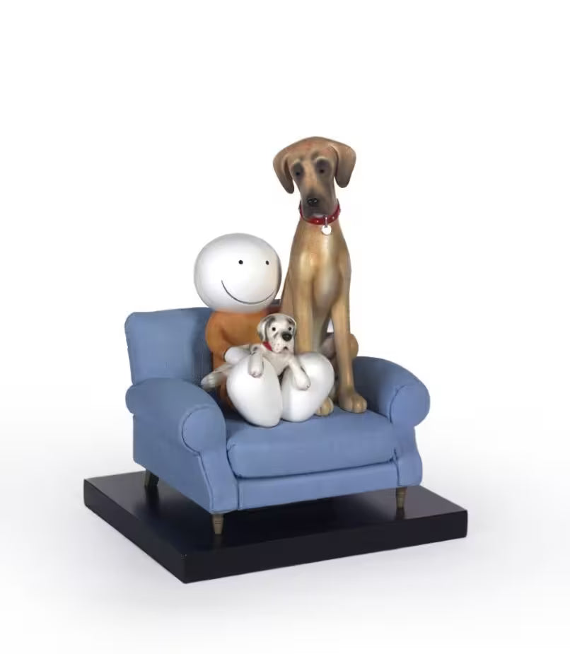 A sculpture by Doug Hyde of a larger dog sitting next to a smaller dog on a blue sofa, with a white base and a red collar on the larger dog, title is Always by your Side
