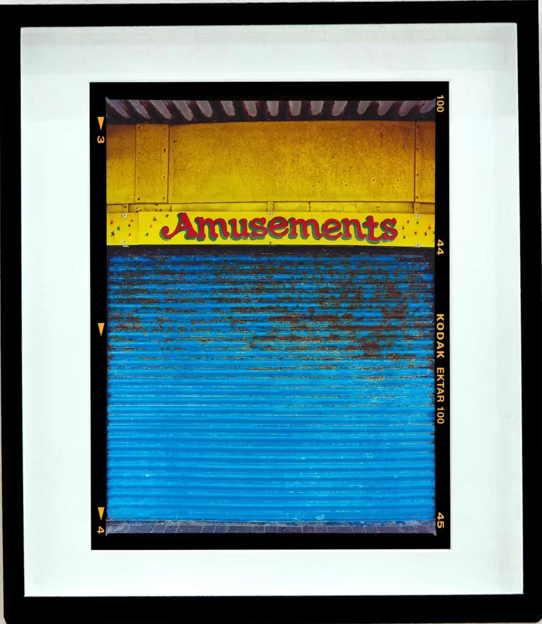A framed limited edition photograph by Richard Heeps using vibrant colours, the title is Amusements, Porthcawl, 2023