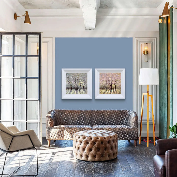 Modern living room with a brown sofa, ottoman, and framed artwork by Inam  on a blue wall.