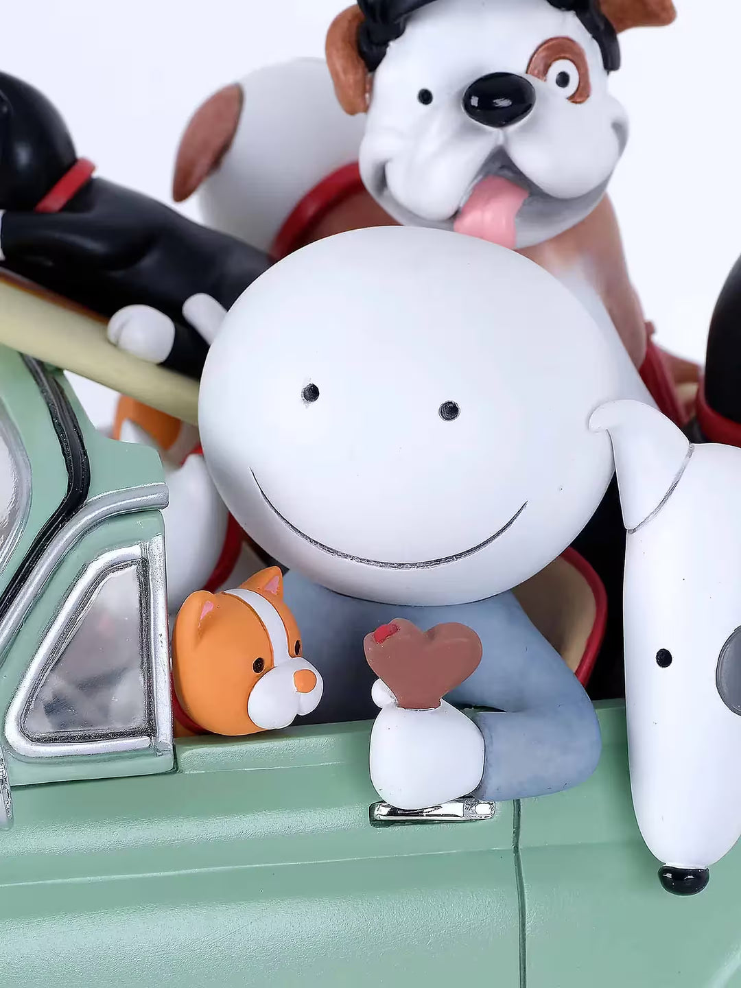 A Doug Hyde porcelain sculpture of a person in a green car with dogs and cats and beach items in the car, the title is Beach Buddies