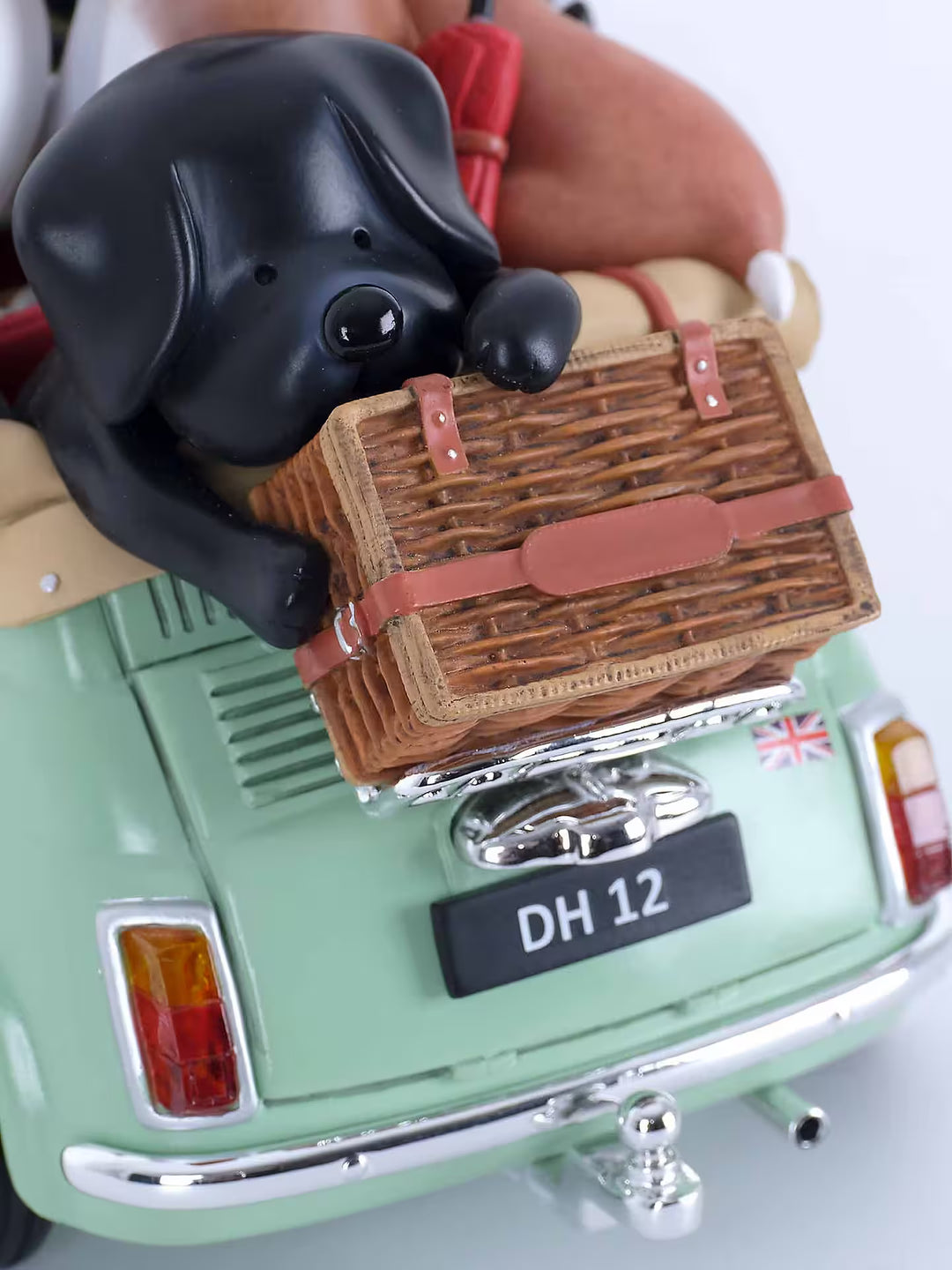 A Doug Hyde porcelain sculpture of a person in a green car with dogs and cats and beach items in the car, the title is Beach Buddies