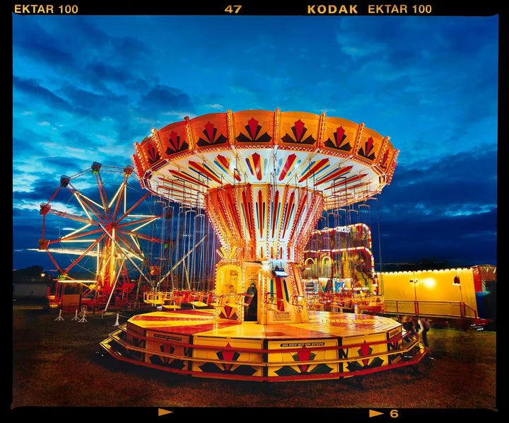 A limited edition photograph by Richard Heeps using vibrant colours, the title is Chairoplanes, Haddenham, 2022