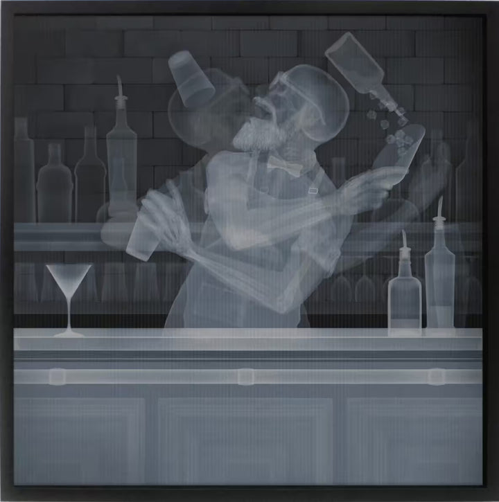 A framed limited edition lenticular print by Nick Veasey of an X-Rayed bartender, their skeleton is doing tricks with their bottles and shakers, the title is Cocktail Flair