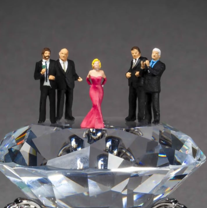 Figurines of people on a large crystal-like object against a grey background, Diamonds Are A Girl&
