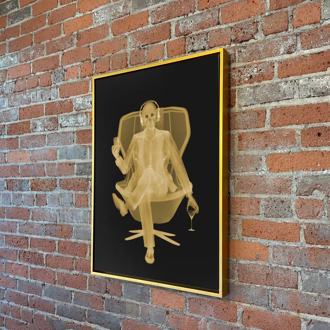 A Nick Veasey limited edition Chromaluxe Xray of a person sat in a chair drinking with headphones on listening to music, the title is Easy Listener- Golden Era