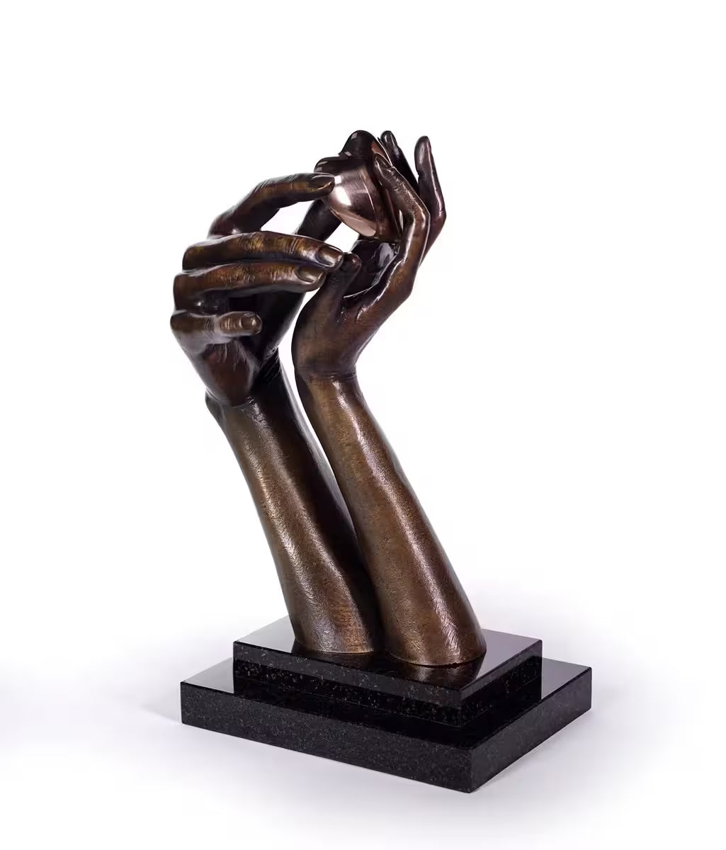 A Michael Talbot limited edition bronze sculpture of two hands holding a gold heart, the title is Forever Love