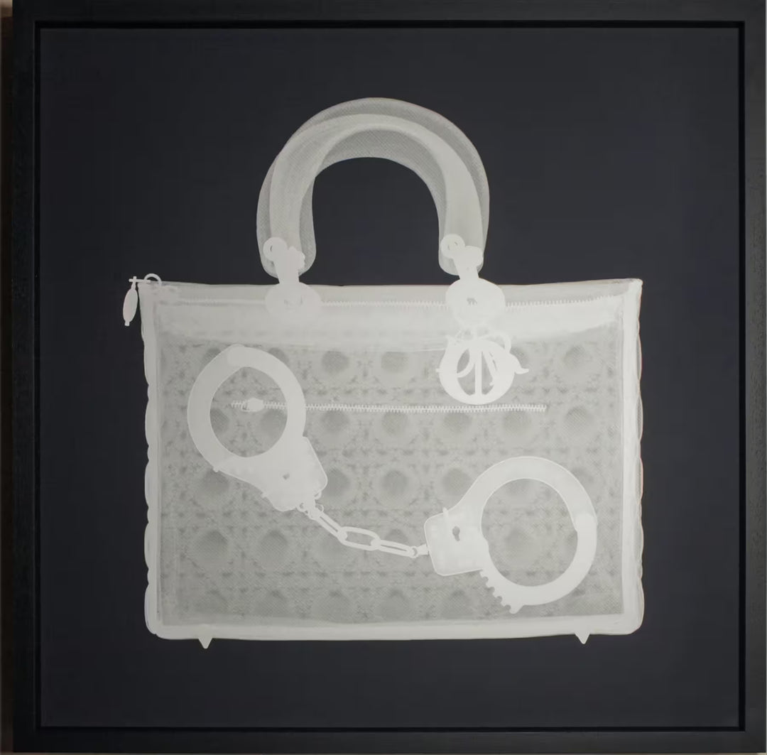 A limited edition framed Silkscreen print by Nick Veasey of an X-Rayed handbag with a pair of handcuffs inside, the title is Handucff Handbag