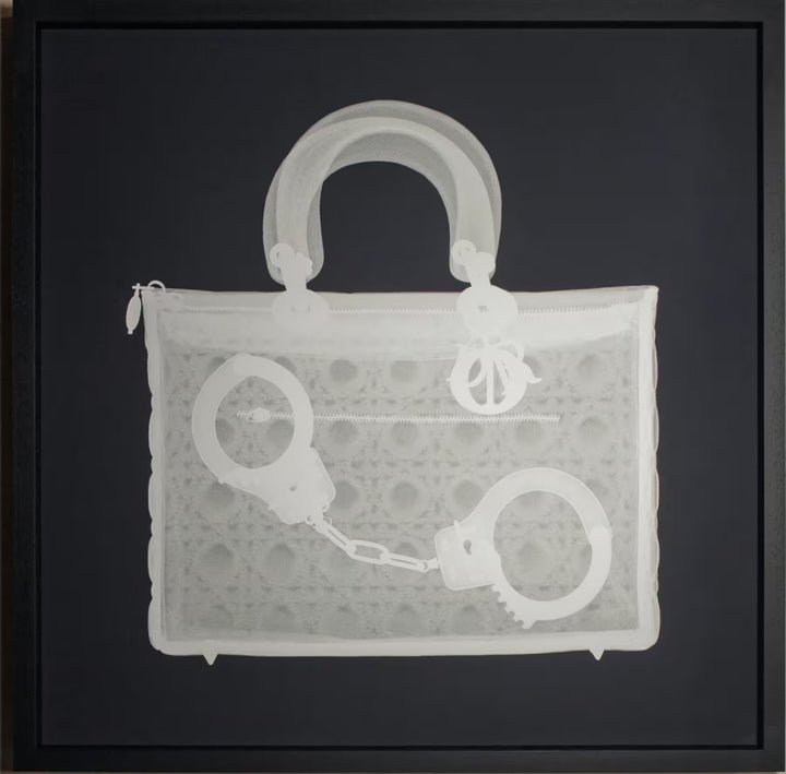 A limited edition framed Silkscreen print by Nick Veasey of an X-Rayed handbag with a pair of handcuffs inside, the title is Handucff Handbag