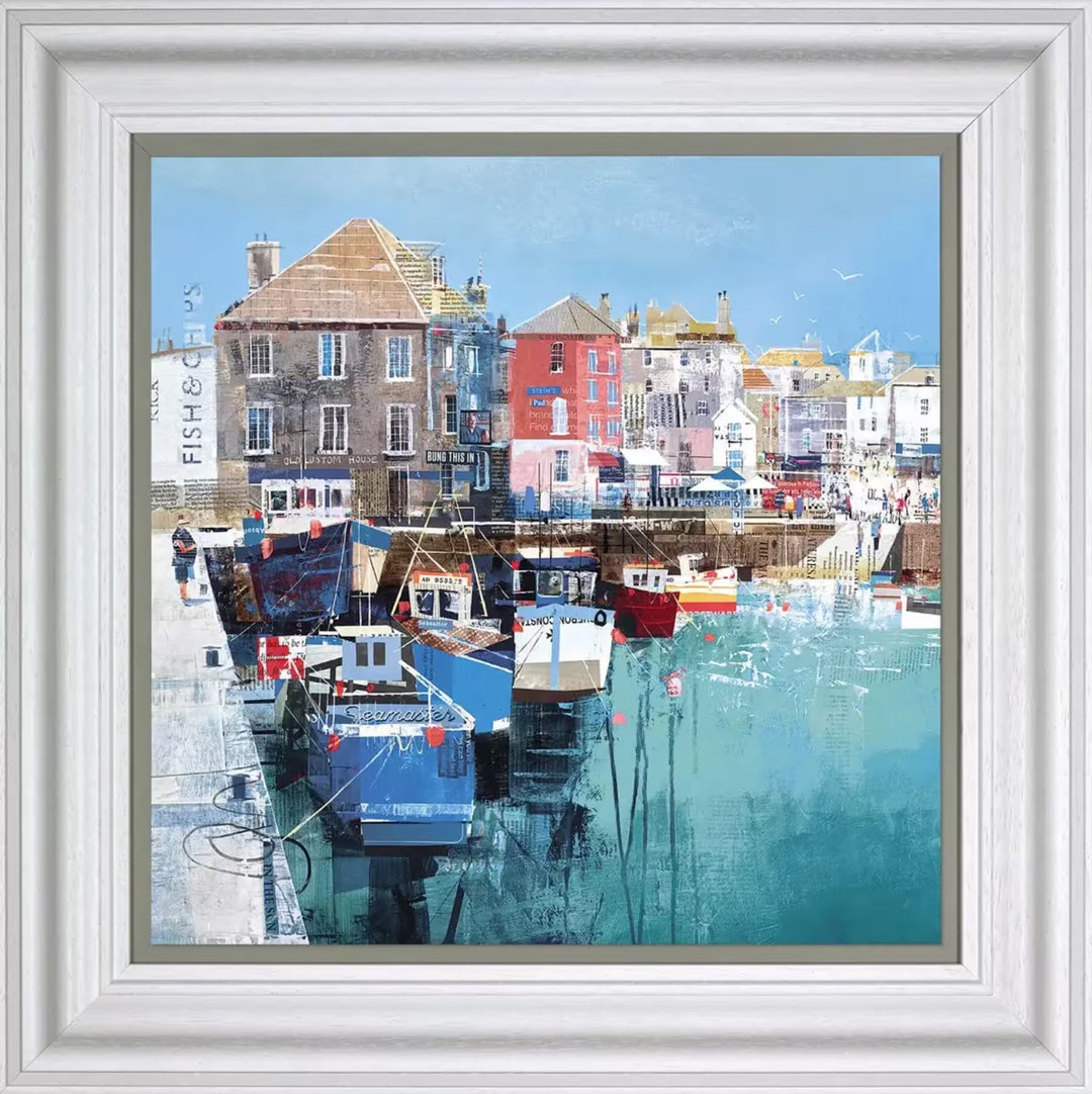 A Tom Butler framed limited edition collage of Padstow, Cornwall. There are boats docked and some buildings behind, all collaged with local magazine and newspapers, the title is Harbour Sun