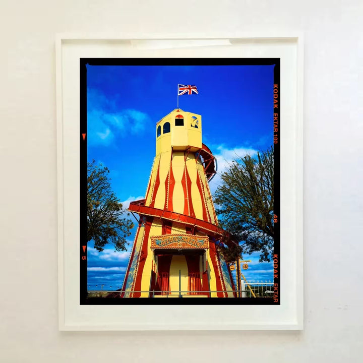 A white framed limited edition photograph by Richard Heeps using vibrant colours, the title is Helter Skelter, Great Yarmouth, 2023