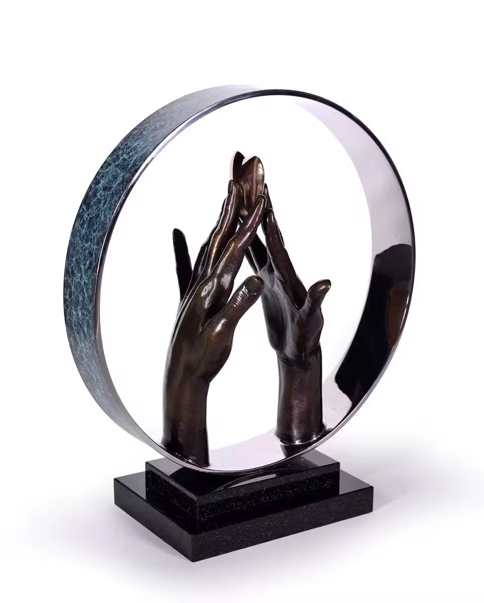 A Michael Talbot limited edition bronze sculpture of two hands holding a gold heart, the title is Infinite Love