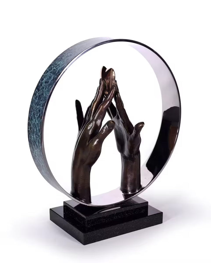 A Michael Talbot limited edition bronze sculpture of two hands holding a gold heart, the title is Infinite Love