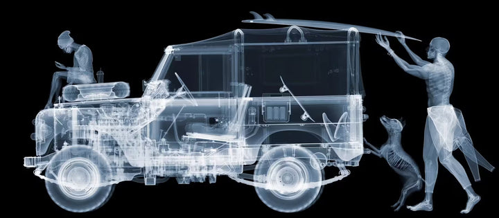 A limited edition Chromaluxe print by Nick Veasey of an X-Rayed vehicle with skeletal people and dog interracting with the vehicle in different ways, the title is Land Rover - Surf and Skate