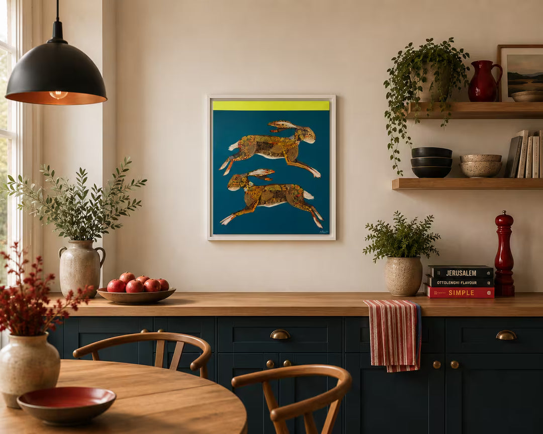 A Nicola Hart original of two hares leaping in front of a teal background, the title is A Merry Dance