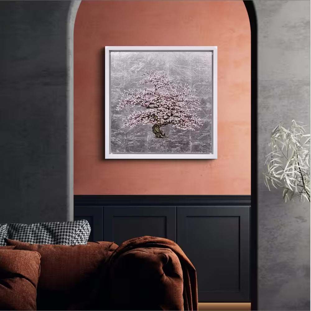 Framed artwork of a cherry blossom tree on a wall with a couch and plant in the foreground. Moonlight by Jack Frame