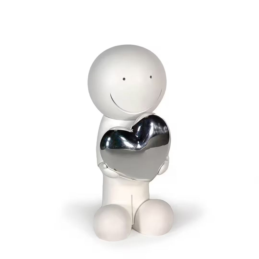 A sculpture by Doug Hyde of a person holding a heart in white and silver, the title is One Love (White & Silver)
