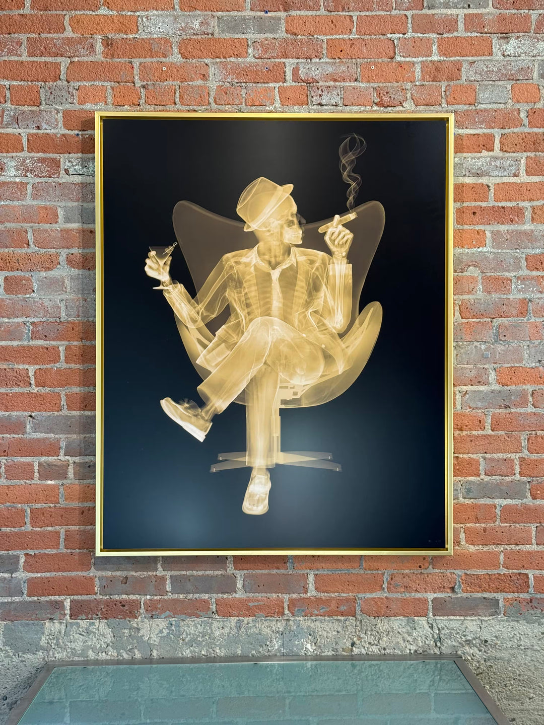 A Nick Veasey limited edition Chromaluxe X ray of a person sat in a chair drinking and smoking a cigar, the title is Rat Pack II- Golden Era