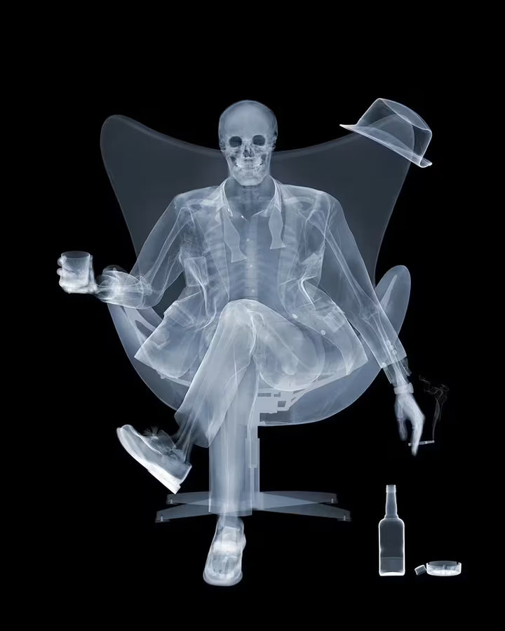 A limited edition lenticular print by Nick Veasey of an X-Rayed ratpack member sat on a big chair raising a drink, the title is Rat Pack Raising A Glass