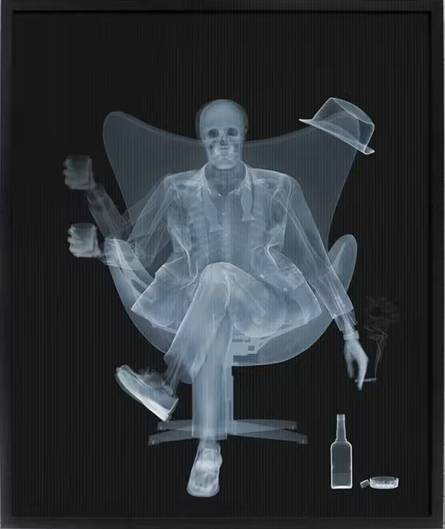 A limited edition framed lenticular print by Nick Veasey of an X-Rayed ratpack member sat on a big chair raising a drink, the title is Rat Pack Raising A Glass