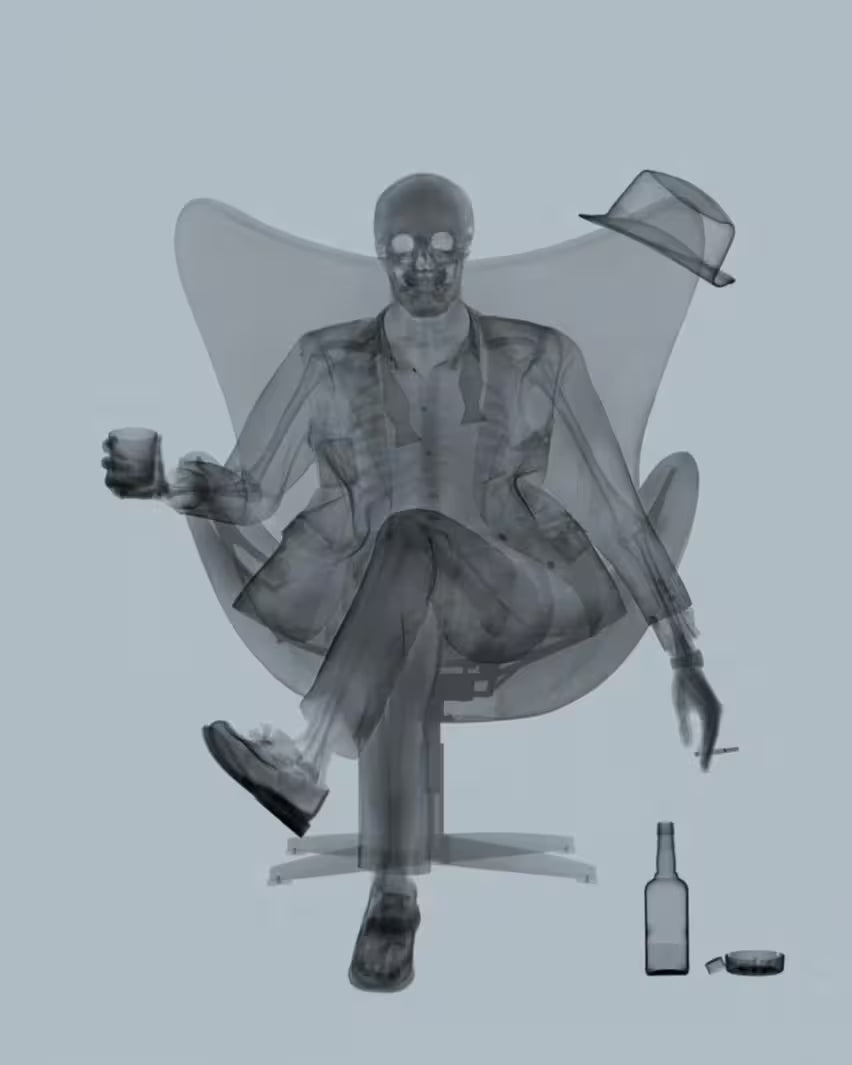 A limited edition Chromaluxe print by Nick Veasey of an X-Rayed ratpack member sat on a big chair with a drink in their hand, the title is Rat Pack Grey