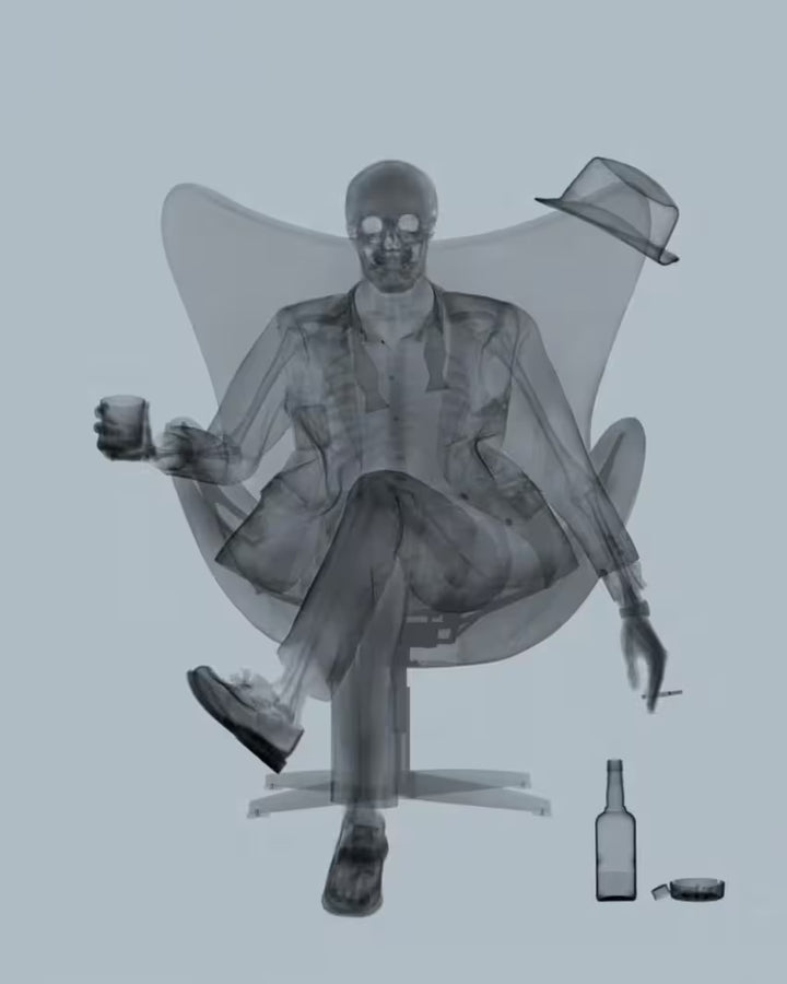 A limited edition Chromaluxe print by Nick Veasey of an X-Rayed ratpack member sat on a big chair with a drink in their hand, the title is Rat Pack Grey