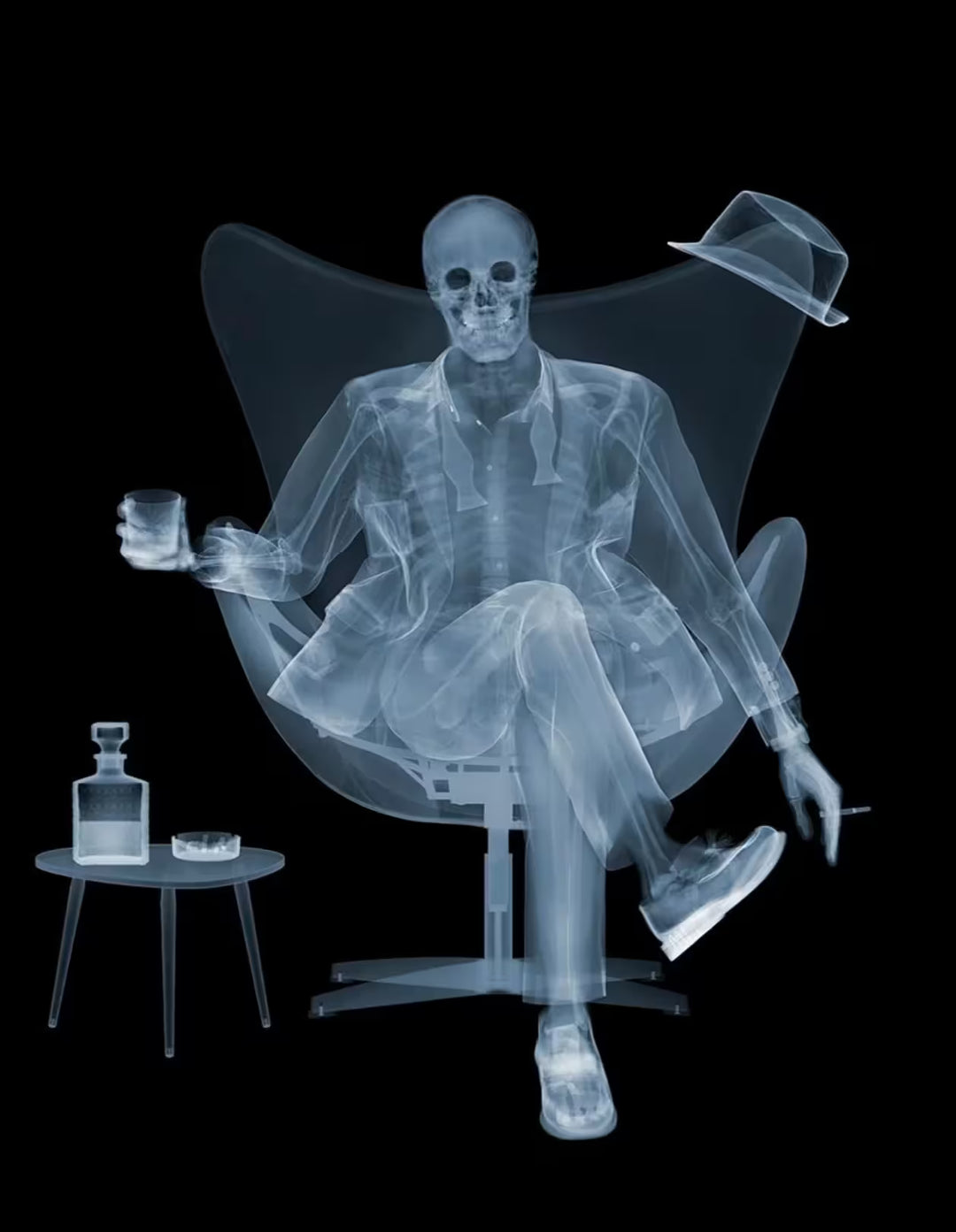 A limited edition Chromaluxe print by Nick Veasey of an X-Rayed ratpack member sat on a big chair with a drink in their hand and a table with a drink. next to them, they are also holding a cigarette, the title is Rat Pack III