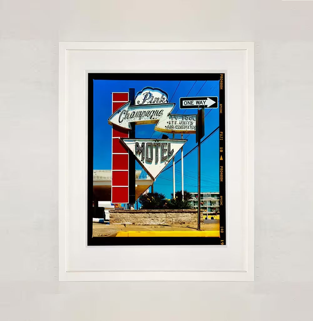 A white framed limited edition photograph by Richard Heeps using vibrant colours, the title is Pink Champagne Motel (Film Rebate), Wildwood Jersey, 2013