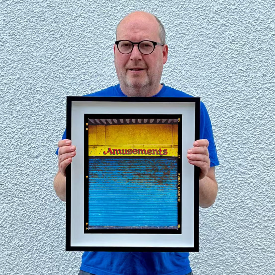Richard holding a limited edition photograph, the title is Amusements, Porthcawl, 2023