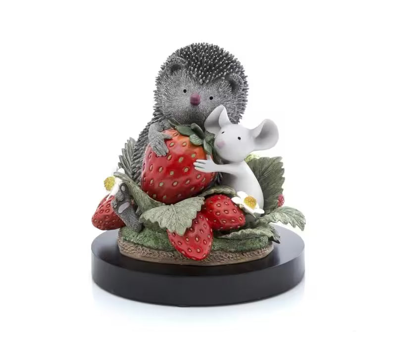 A sculpture by Doug Hyde of a hedgehog and white mouse sat in a strawberry patch hugging a big red strawberry, the title is Sharing is Caring
