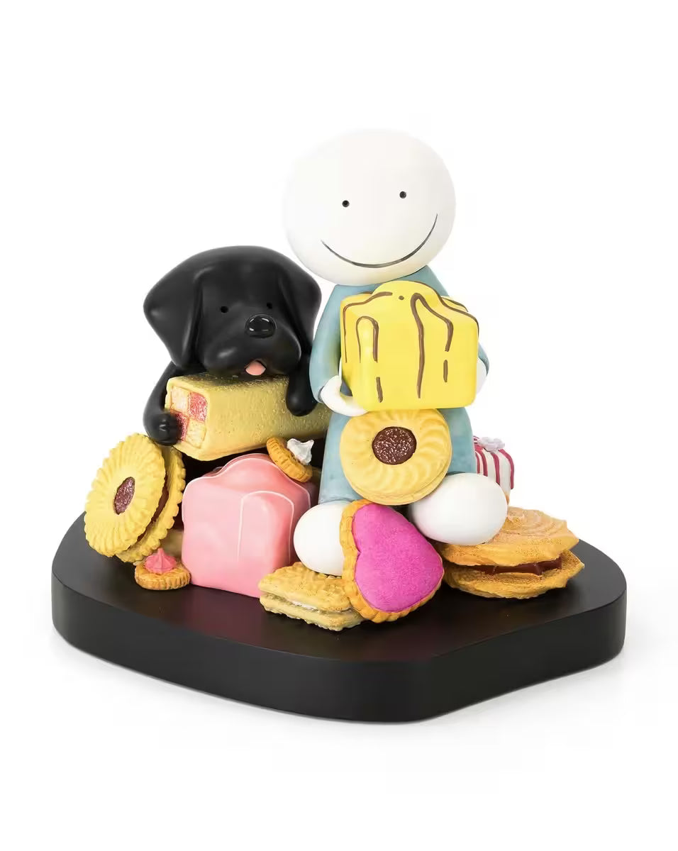 A sculpture by Doug Hyde of a person and black dog sat on a pile of biscuits and cakes whilst holding a cake each, the title is Sweet Talk