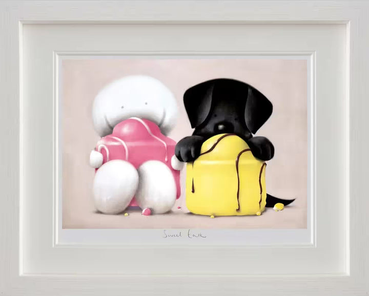 A Doug Hyde framed limited edition of a person and black dog sat with big cakes on their laps and crumbs around them, the title is Sweet Talk