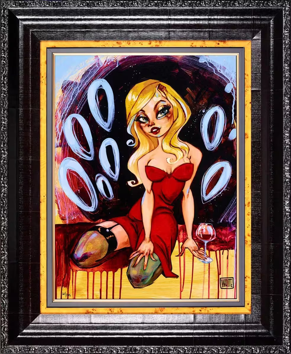 A Todd White framed limited edition piece of a blonde woman in a red dress and a glass of wine kneeling down, the title is The Voodoo That You Do