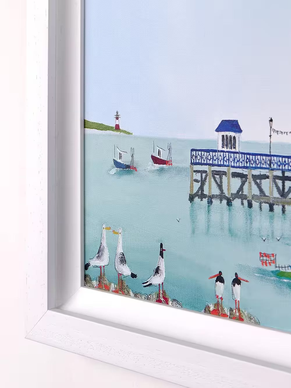 A Rebecca Lardner limited edition piece of a row of colourful houses with a pier at the end and people on the beach and boats on the sea with puffins, seagulls, and avocets on the rocks, the title is Tide and Seek