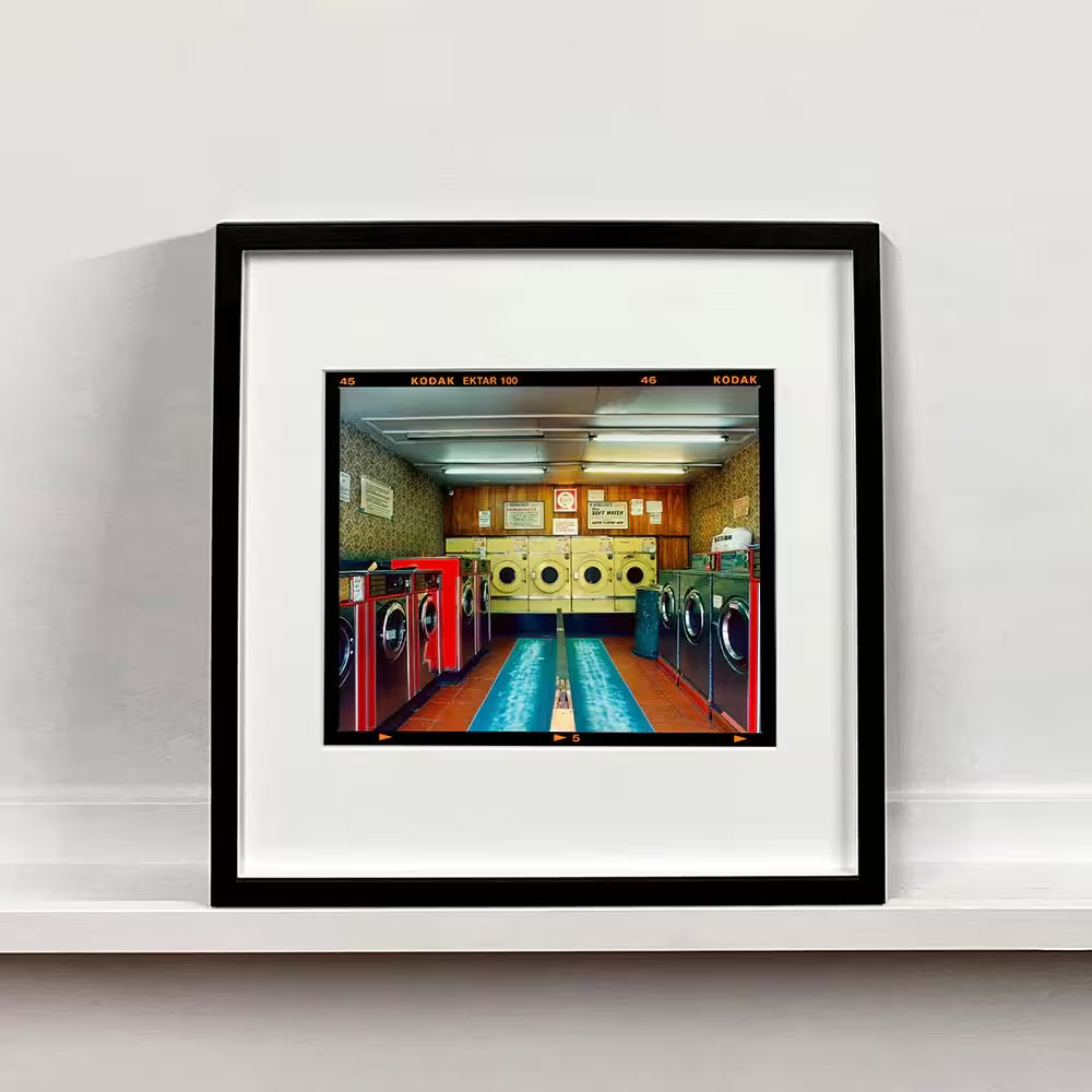 A framed limited edition photograph by Richard Heeps using vibrant colours, the title is Washeteria- Looking In, London, 2020