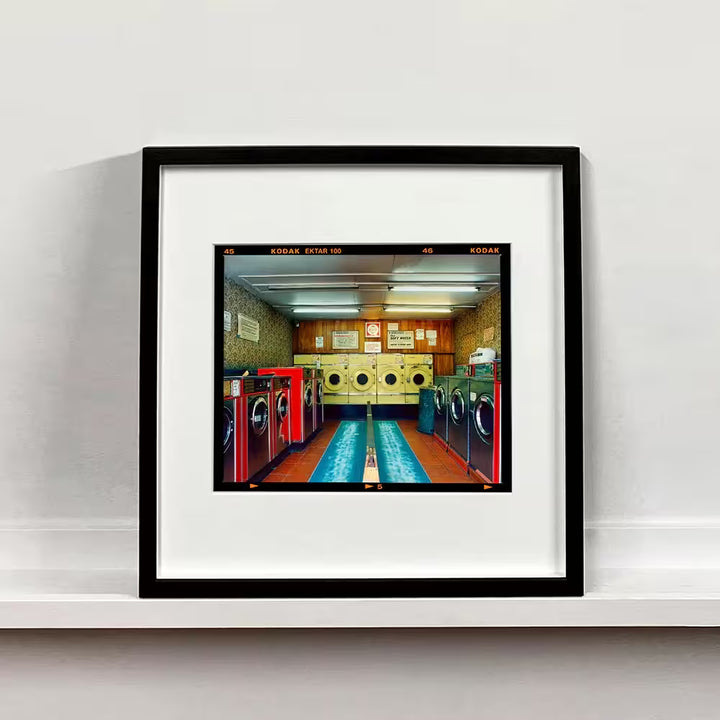 A framed limited edition photograph by Richard Heeps using vibrant colours, the title is Washeteria- Looking In, London, 2020