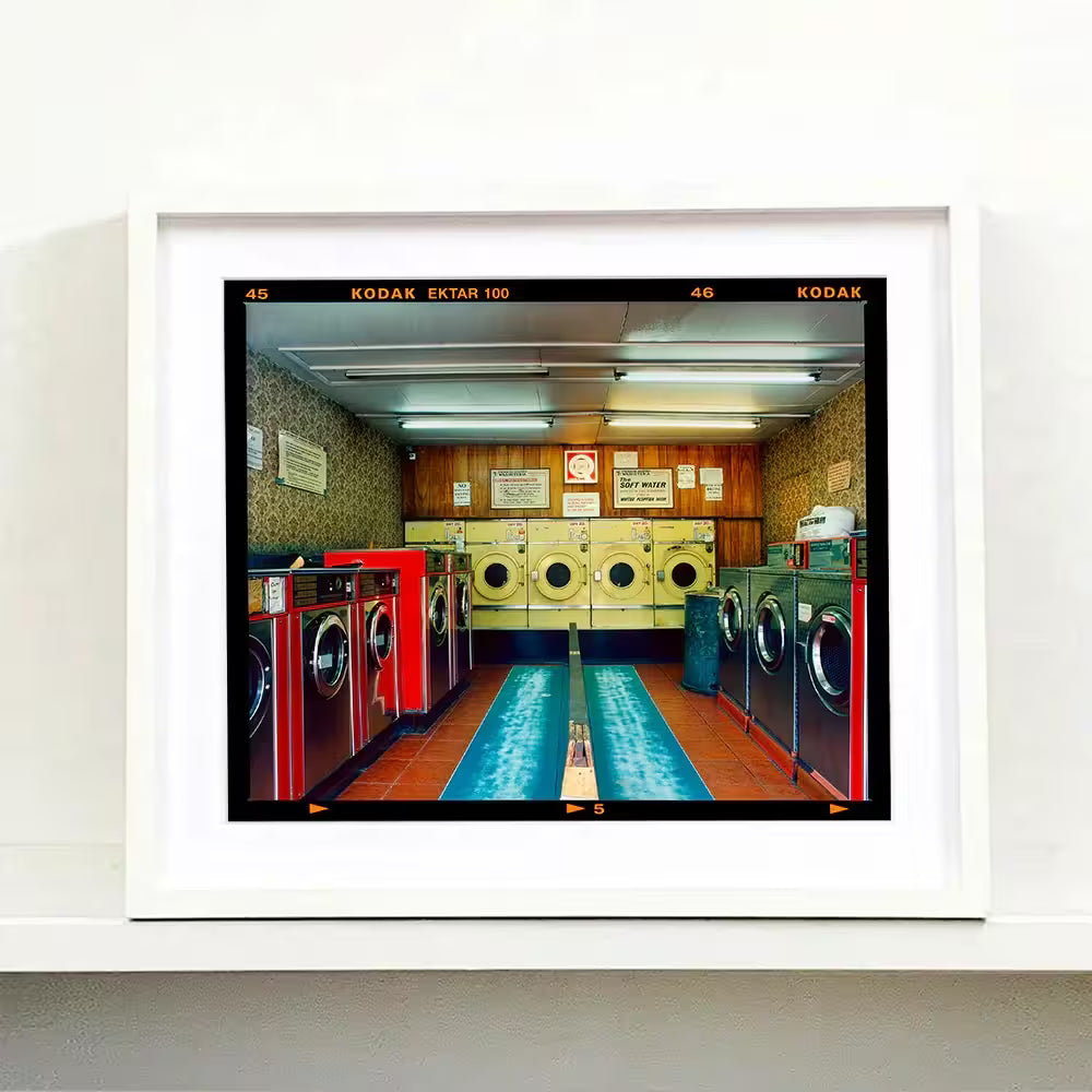 A white framed limited edition photograph by Richard Heeps using vibrant colours, the title is Washeteria- Looking In, London, 2020