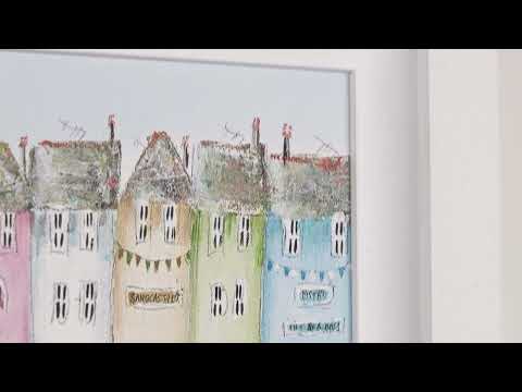 A Rebecca Lardner limited edition piece of a row of colourful houses with a pier at the end and people on the beach and boats on the sea with puffins, seagulls, and avocets on the rocks, the title is Tide and Seek